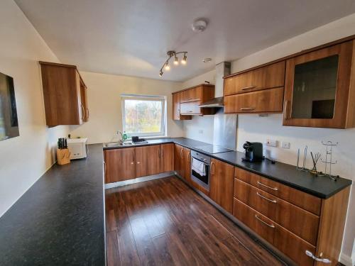 a kitchen with wooden cabinets and a black counter top at Lovely 3 Bed Close to Centre by City SuperHost in Manchester