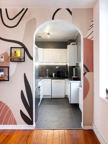 une cuisine avec des placards blancs et un mur rose dans l'établissement L'Ecrin Mosellan, à Ban-Saint-Martin