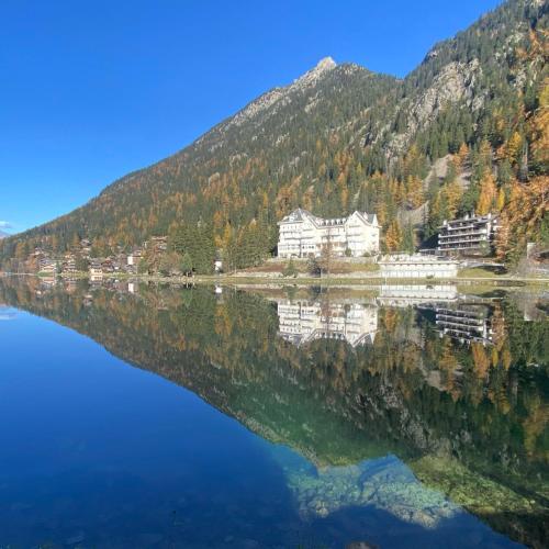 a reflection of a house on a lake in the mountains at Petit Canada - Studio à louer in Champex