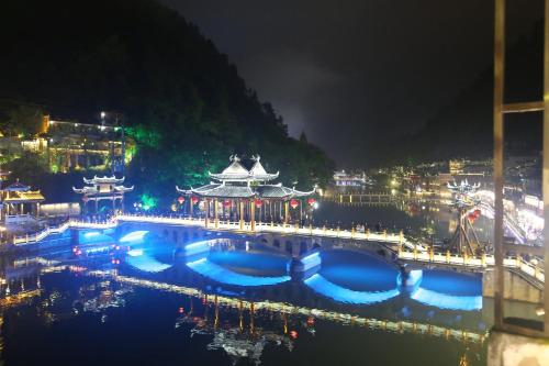 a bridge over a river with a city at night at LQJ Riverside Guest House in Fenghuang