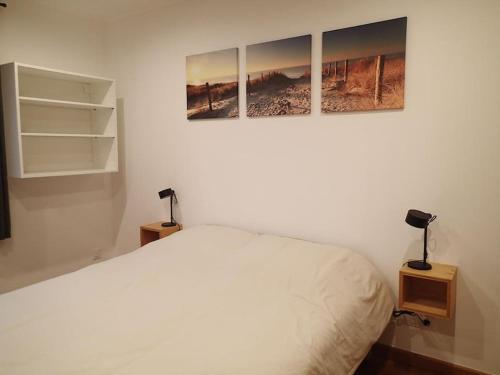 une chambre avec un lit blanc avec trois tableaux au mur dans l'établissement Une fenêtre à la campagne, à Saint-Désir