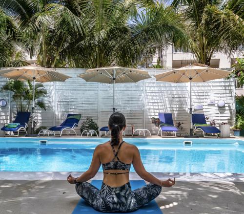 a woman doing yoga by a swimming pool at Bleu de Toi Boutique Hotel in Grand Baie