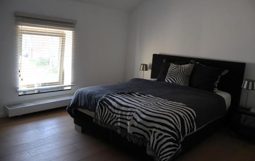 a zebra print bed in a bedroom with a window at Maison Quatre-Vingt-Deux in Maasmechelen
