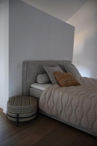 a bed with a pillow and a stool in a room at Maison Quatre-Vingt-Deux in Maasmechelen
