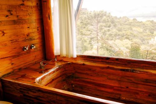 a wooden sink in a window with a view at Chalés Recanto do Vale - GRALHA AZUL in Bom Jardim da Serra