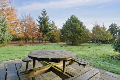 a wooden picnic table with benches and a field at Relaxing Holiday Home Near Water And Jesperhus in Roslev