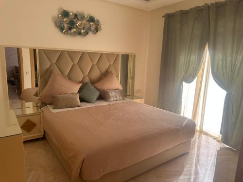 a bedroom with a large bed with a large window at superbe appartement en résidence balnéaire in Bouznika