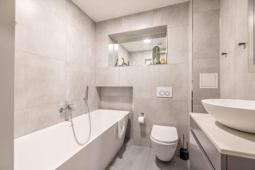 a bathroom with a sink and a tub and a toilet at Modern 2 Bed Oasis - Private parking & Garden in Windsor
