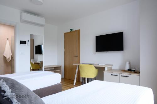 a hotel room with two beds and a flat screen tv at Hiša Janko in Dolenjske Toplice