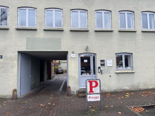 a parking meter in front of a building with a parking garage at 11A Højbanetorvet in Vejle