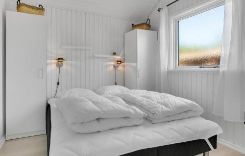 a bed with white sheets and a window in a room at 3 Bedroom Nice Home In Melby in Melby