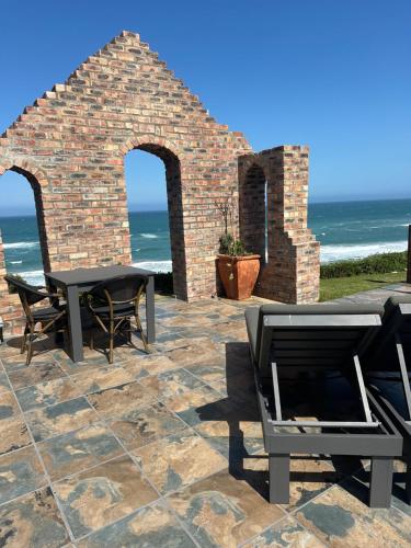 a patio with a table and chairs and the ocean at Mes Amis Beach Guest House in Wilderness