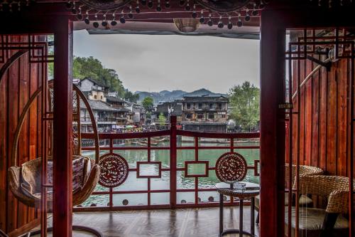 a balcony with chairs and a view of a river at LQJ Riverside Guest House in Fenghuang