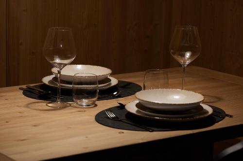 a wooden table with plates and wine glasses on it at Bormio Cozy Gem in Bormio