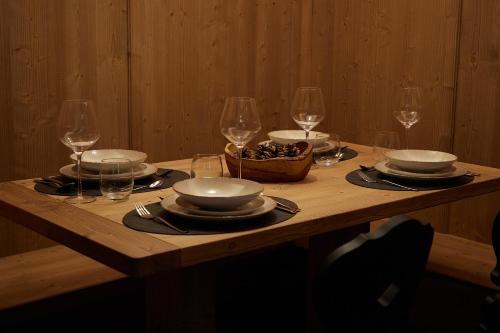 a wooden table with plates and wine glasses on it at Bormio Cozy Gem in Bormio