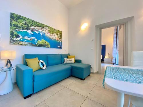 a living room with a blue couch and a table at Alla Casa Rosa al Mare, Central Seafront Stay, Air Conditioning, Wi-Fi, the Ideal Choice for a Relaxing and Exciting Coastal Escape, with available on request at 20,00 euro per night Private Garage, Welcome kit Priority, Prosecco and Canestrelli in Rapallo