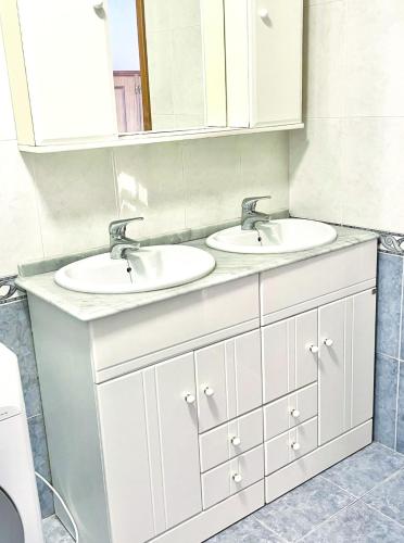 a bathroom with two sinks and a mirror at Cozy Carcavelos Beach-NOVA SBE in Carcavelos