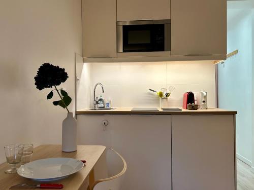 une petite cuisine avec une table et un vase de fleurs dans l'établissement Fully equipped Studio near metro, à Paris