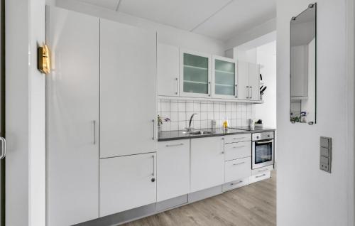 a white kitchen with white cabinets and a sink at Fanø Bad, Lejl 57 in Fanø