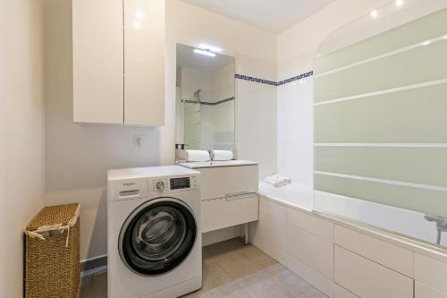- une buanderie blanche avec un lave-linge et une baignoire dans l'établissement Oasis Lumineux and the Natural Home a Paris - 8 PAX - 2BR, à Saint-Ouen