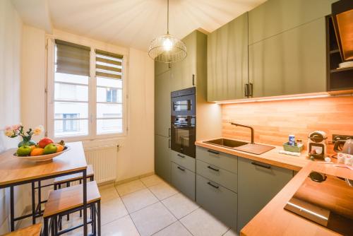 - une cuisine avec des placards verts et une table avec un bol de fruits dans l'établissement Le Voltaire - Hypercentre - Netflix, à Tours