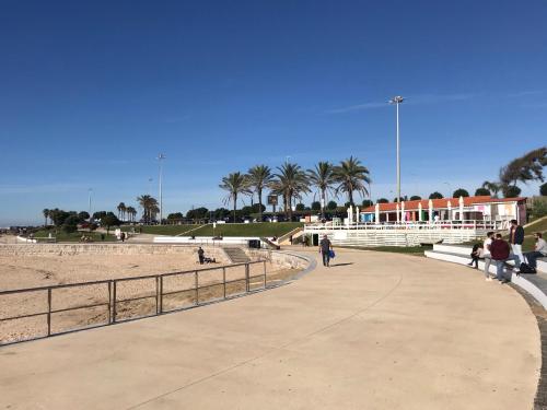 people walking on a sidewalk next to the beach at Cozy Carcavelos Beach-NOVA SBE in Carcavelos