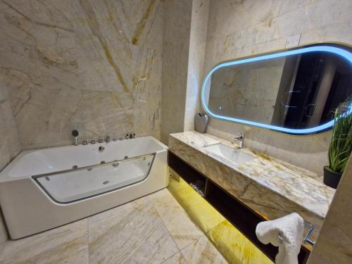 a bathroom with a tub and a sink and a mirror at Ocean View Hotel Kuwait in Kuwait