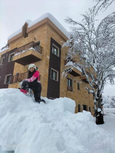 a woman sitting on top of a pile of snow at Rokwood faraya in Ash Sha‘rah