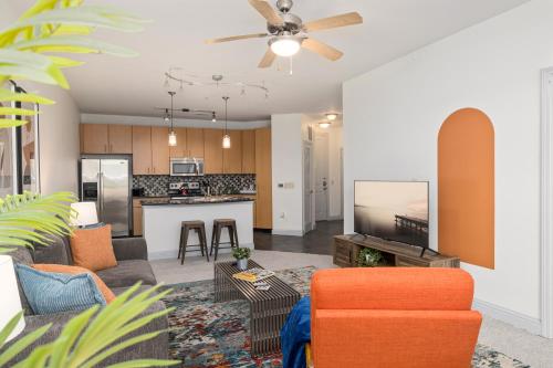 an open living room and kitchen with an orange chair at League Flats South End on South College Street in Charlotte
