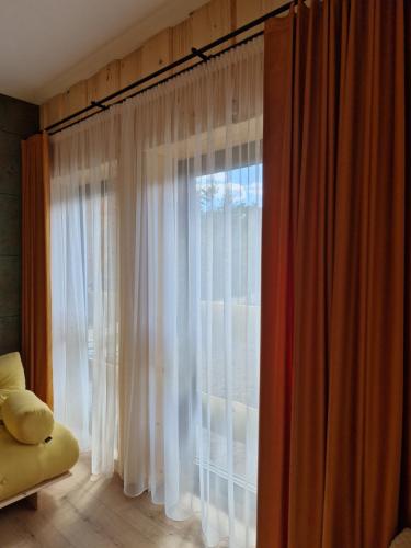 a room with a large window with white curtains at Chata Braci Warchały in Warchały
