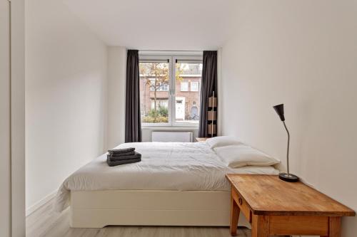 a white bedroom with a bed and a table at Hertog 2 in Eindhoven