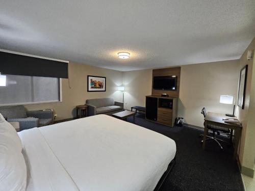 a hotel room with a white bed and a desk at Baymont by Wyndham Davenport in Davenport