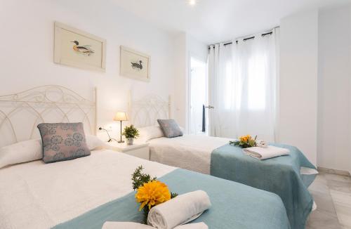 a white bedroom with two beds with flowers on them at Vistahermosa Piscina Vistas in El Puerto de Santa María