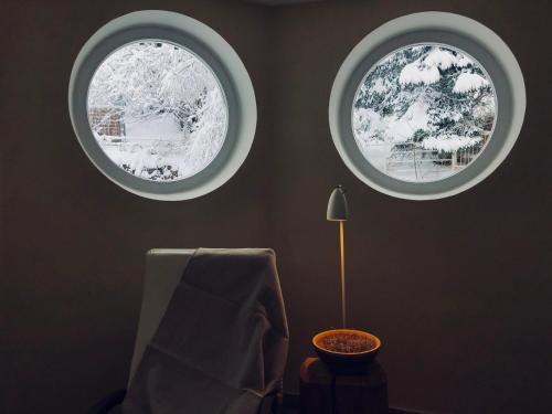 two round windows in a room with a chair and a lamp at Stern B&B & Suite Apartments in Nova Levante
