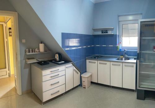 a blue kitchen with white cabinets and a sink at Pronto in Kikinda