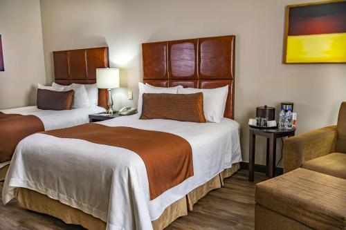a hotel room with two beds and a chair at Best Western PLUS Monterrey Airport in Monterrey