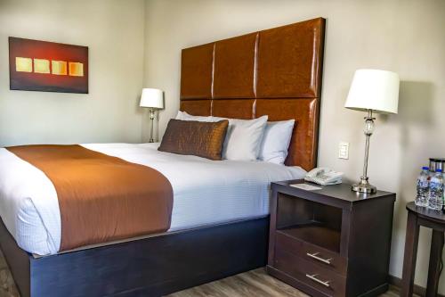 a hotel room with a large bed with a wooden headboard at Best Western PLUS Monterrey Airport in Monterrey