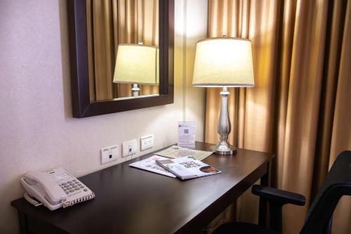 a hotel room with a desk with a telephone and a mirror at Best Western PREMIER Monterrey Aeropuerto in Monterrey