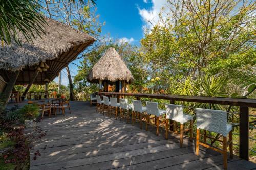 a deck with chairs and a bar with a thatch roof at C-View Villas in Nusa Lembongan