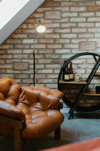 a brown leather couch in a room with a brick wall at Ady54 in Tata