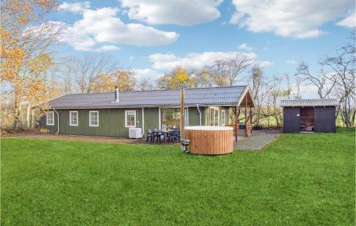 a green house in a field with a yard at Stunning Home In Nibe With Kitchen in Store Ajstrup