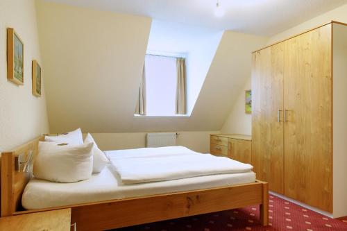 a bedroom with a bed with white sheets and a window at Eisenberger Hof in Moritzburg