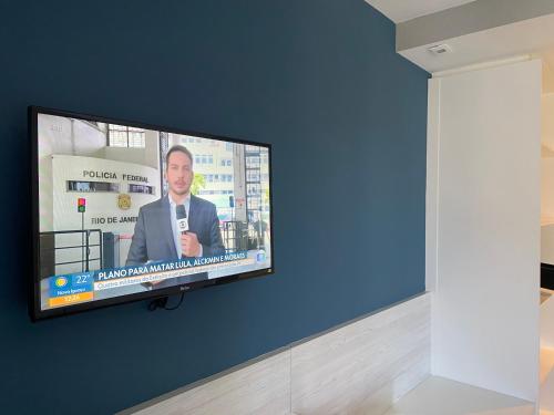 a flat screen tv hanging on a blue wall at Hotel em CABO FRIO Cond Royale - Av Assunção 239 Bairro Passagem ap 305 in Cabo Frio