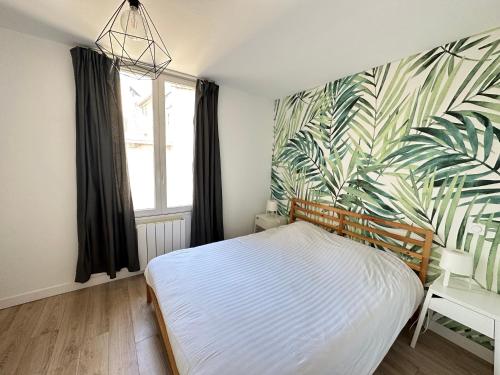 a bedroom with a bed and a tropical wallpaper at Le Forum - HYPER centre - PARKING in Reims
