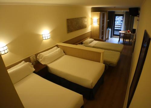 a hotel room with three beds and a table at Yomo Patagonia in Arinsal