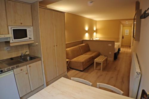 a kitchen and a living room with a couch and a microwave at Yomo Patagonia in Arinsal