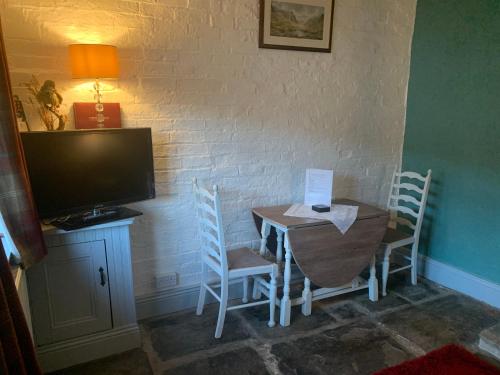 a room with a table and chairs and a television at The Old Stables in Barnsley