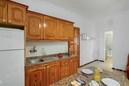 a kitchen with wooden cabinets and a sink at Apartamento Los Angeles 2 in Puerto de Mogán