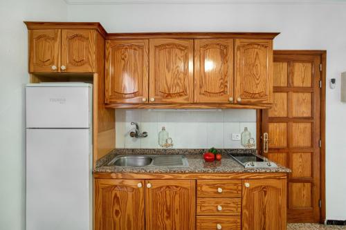 a kitchen with wooden cabinets and a sink and a refrigerator at Apartamento Los Angeles 2 in Puerto de Mogán