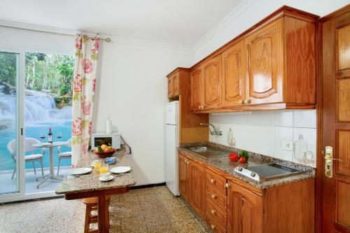 a kitchen with wooden cabinets and a table and a window at Apartamento Los Angeles 2 in Puerto de Mogán